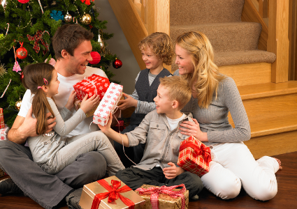 Family exchanging gifts in front of a Christmas tree